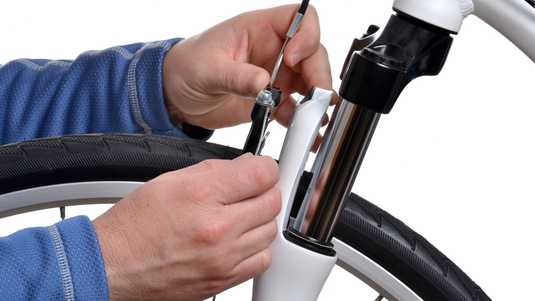 Hands Tightening Brake Cable During Bike Tune Up 